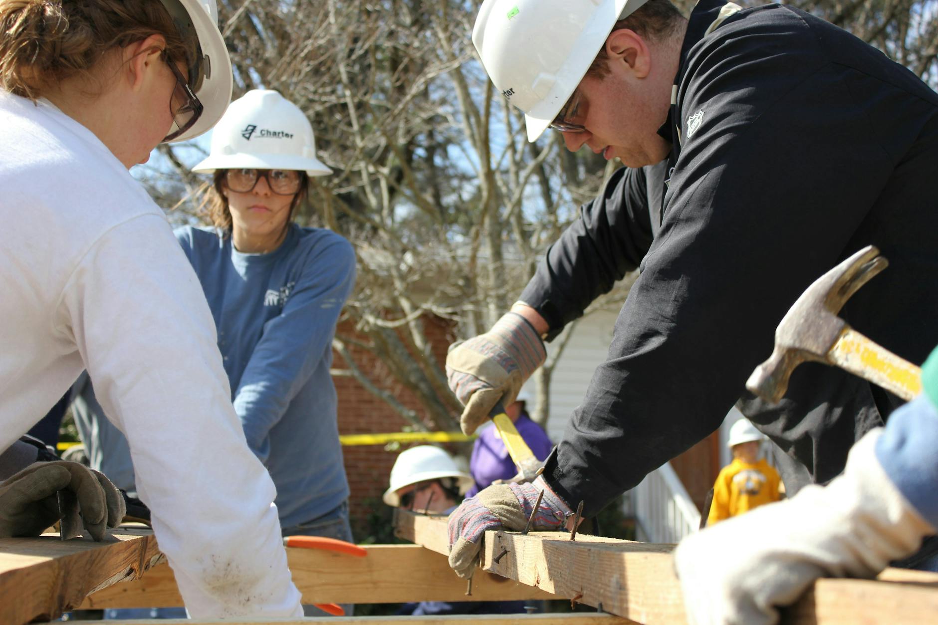 Volunteers work together building a house frame in Raleigh, NC under sunny skies.