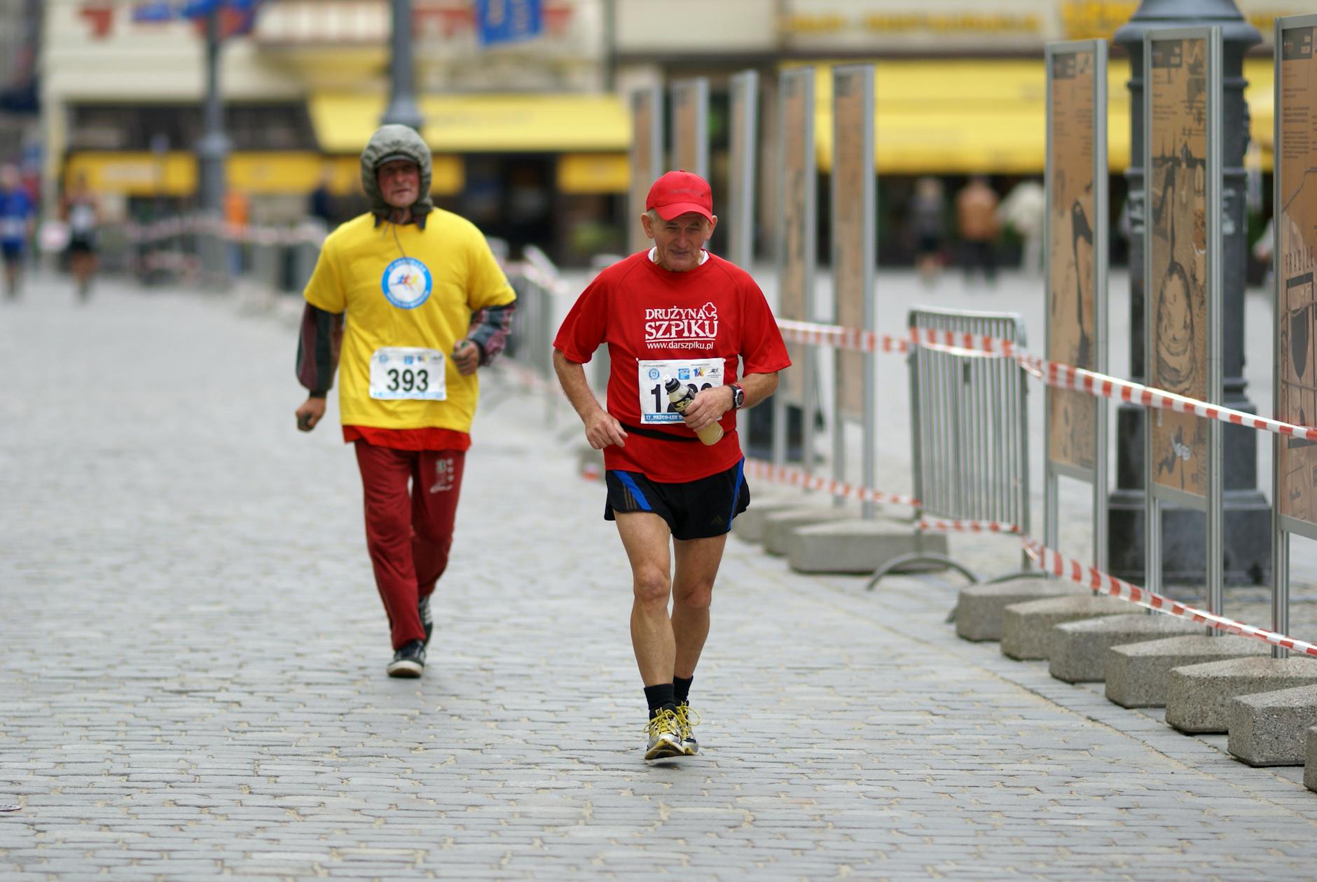 Two adult male competitors running in an urban marathon race, showcasing endurance and competition.