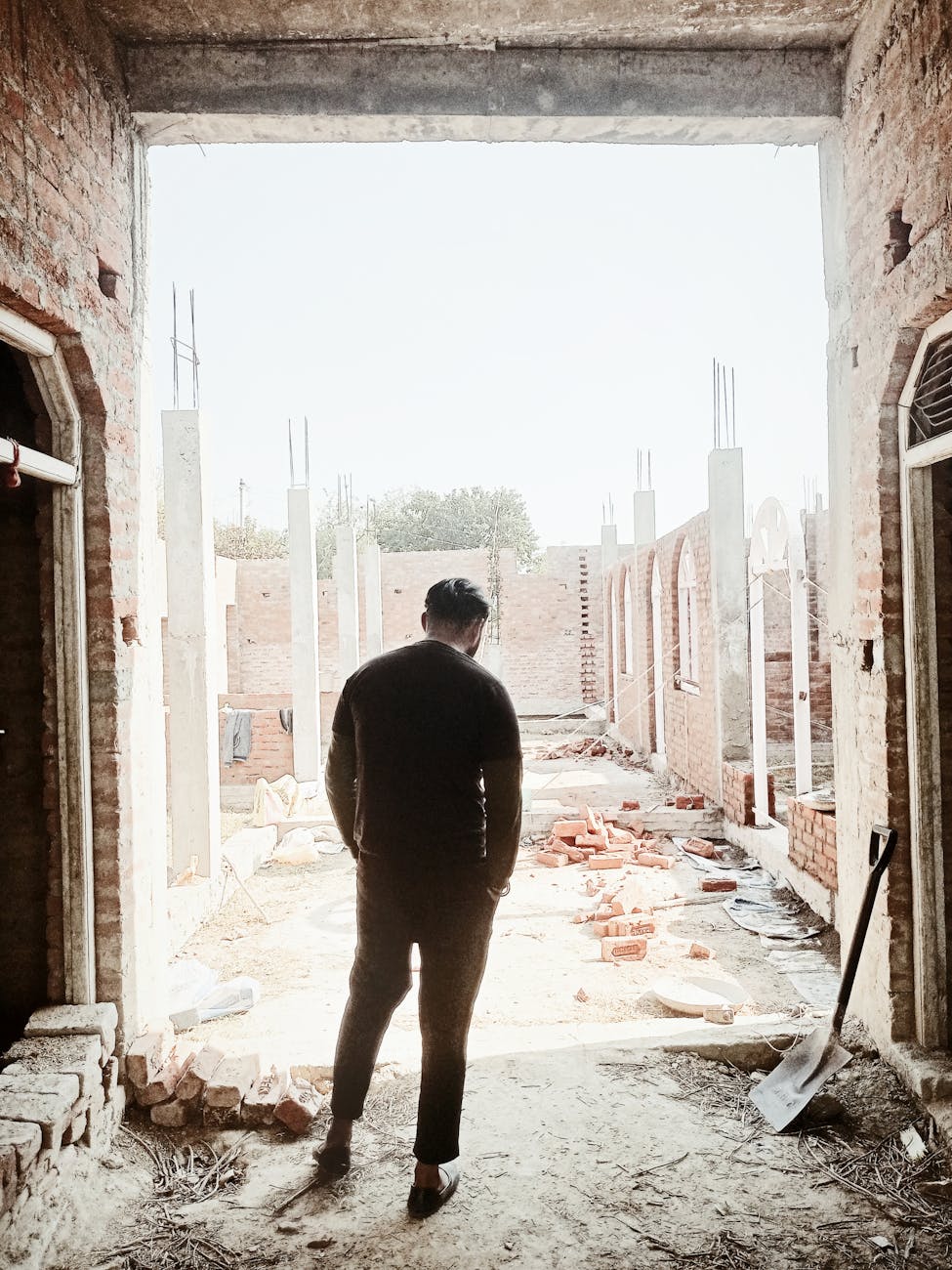 Back view of a man standing at a construction site in Barwaliya, UP, India.