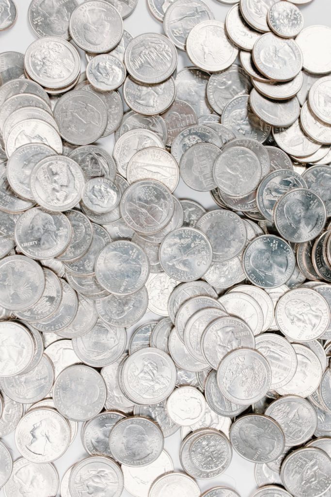 A large collection of silver coins scattered randomly on a white background.