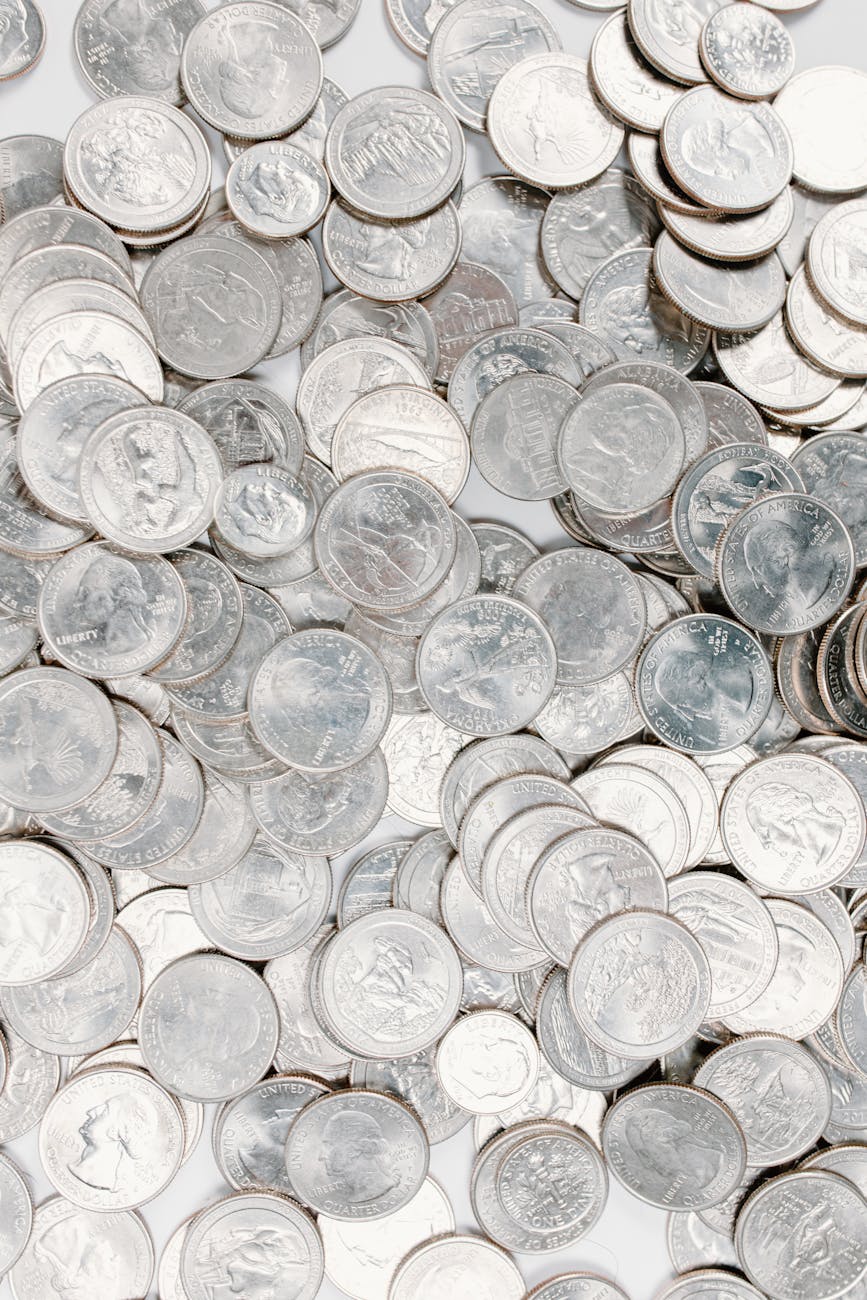A large collection of silver coins scattered randomly on a white background.
