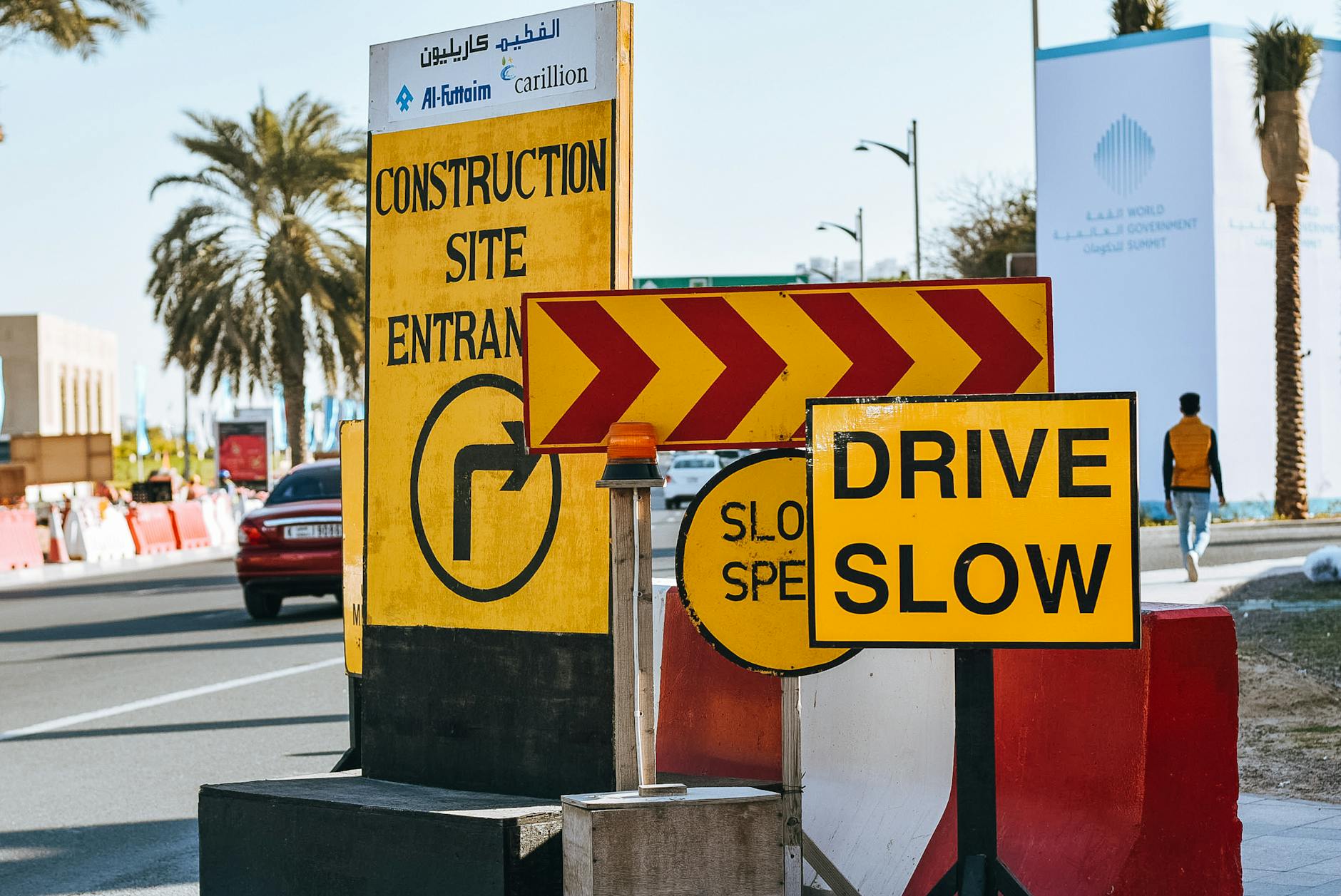 Contemporary city road on sunny day with various traffic signs warning about driving slow because of construction site entrance