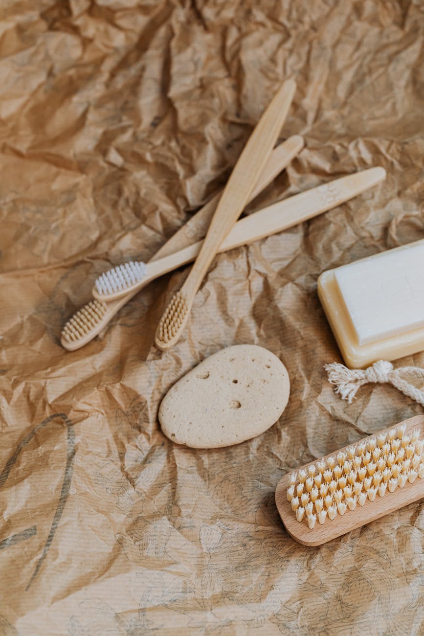 Minimalist arrangement of eco-friendly toothbrushes, soap, and pumice on kraft paper.